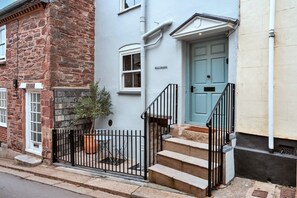 A townhouse with a brick facade, a light blue door, and a small front garden with a potted plant. - Kingsand Coastal Retreat for 6 (Torpoint)