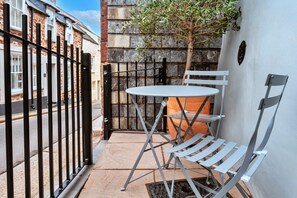 A small outdoor seating area with a metal table and chairs, a metal bench, and a stone wall. - Kingsand Coastal Retreat for 6 (Torpoint)