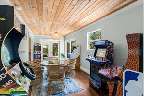 Een kamer met een houten plafond, een ronde tafel met stoelen en speelautomaten.