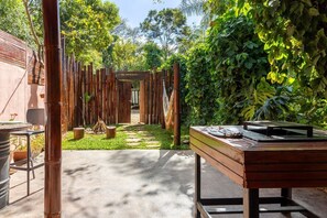 An outdoor area with a concrete path, bamboo fence, and a table with items on it.