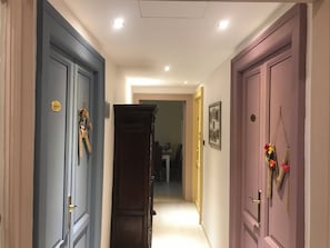 A hallway with three doors, each with a different color and a small decorative item on the door. - In the heart of 19th-century Rome, a spacious apartment for families and groups (Roma)