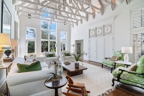 A spacious living room with white furniture, large windows, and a high ceiling with exposed beams. - Light-filled oasis in the Texas Hill Country (San Antonio)