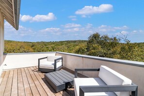 A rooftop terrace with a wooden deck, two white sofas, and a dark table. - Light-filled oasis in the Texas Hill Country (San Antonio)