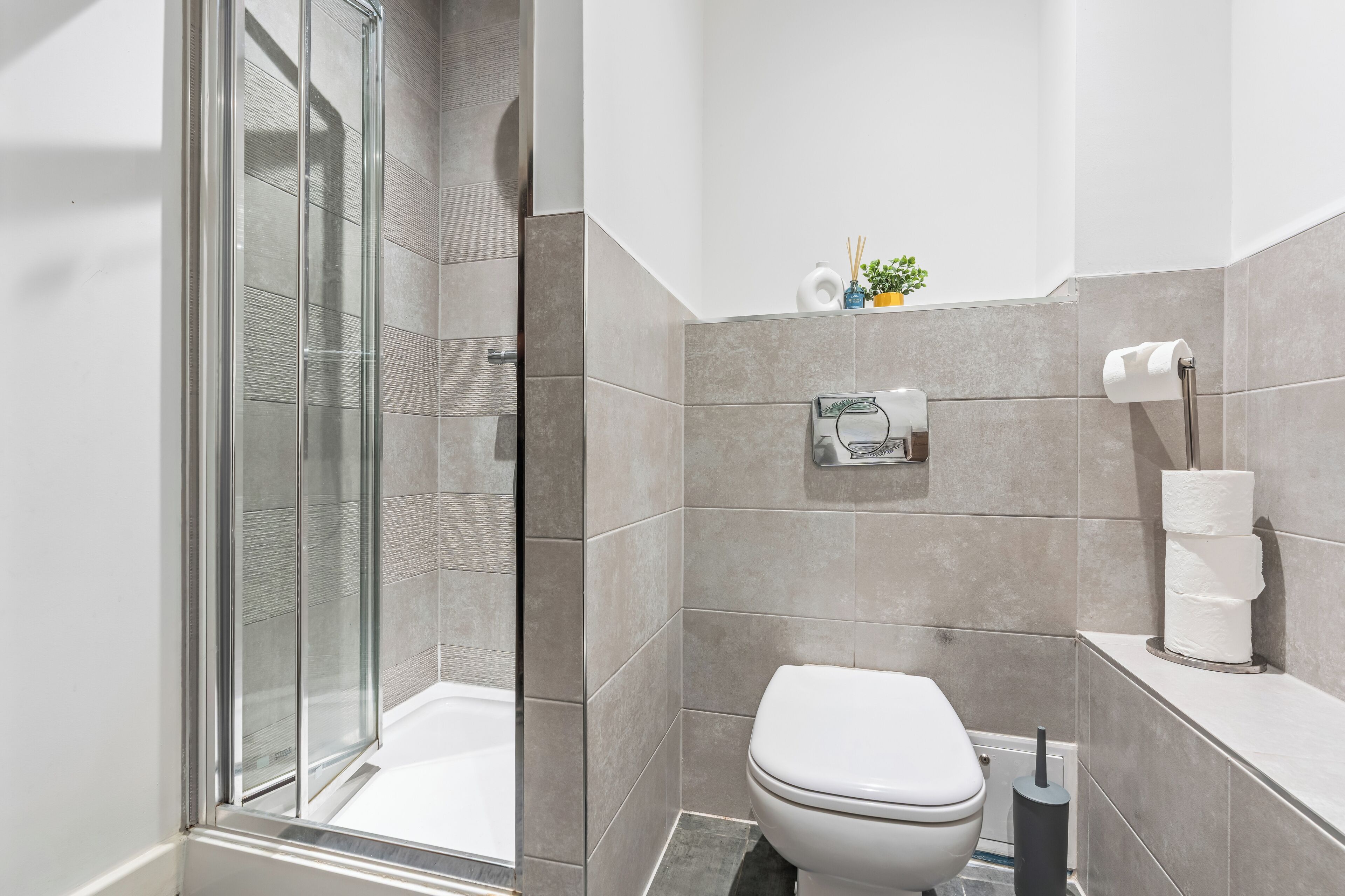 Ein modernes Badezimmer mit Duschkabine aus Glas, Toilette und Waschbecken.
