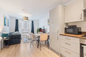 Eine moderne Küche mit Mikrowelle, Schränken und einem Essbereich mit Tisch und Stühlen.