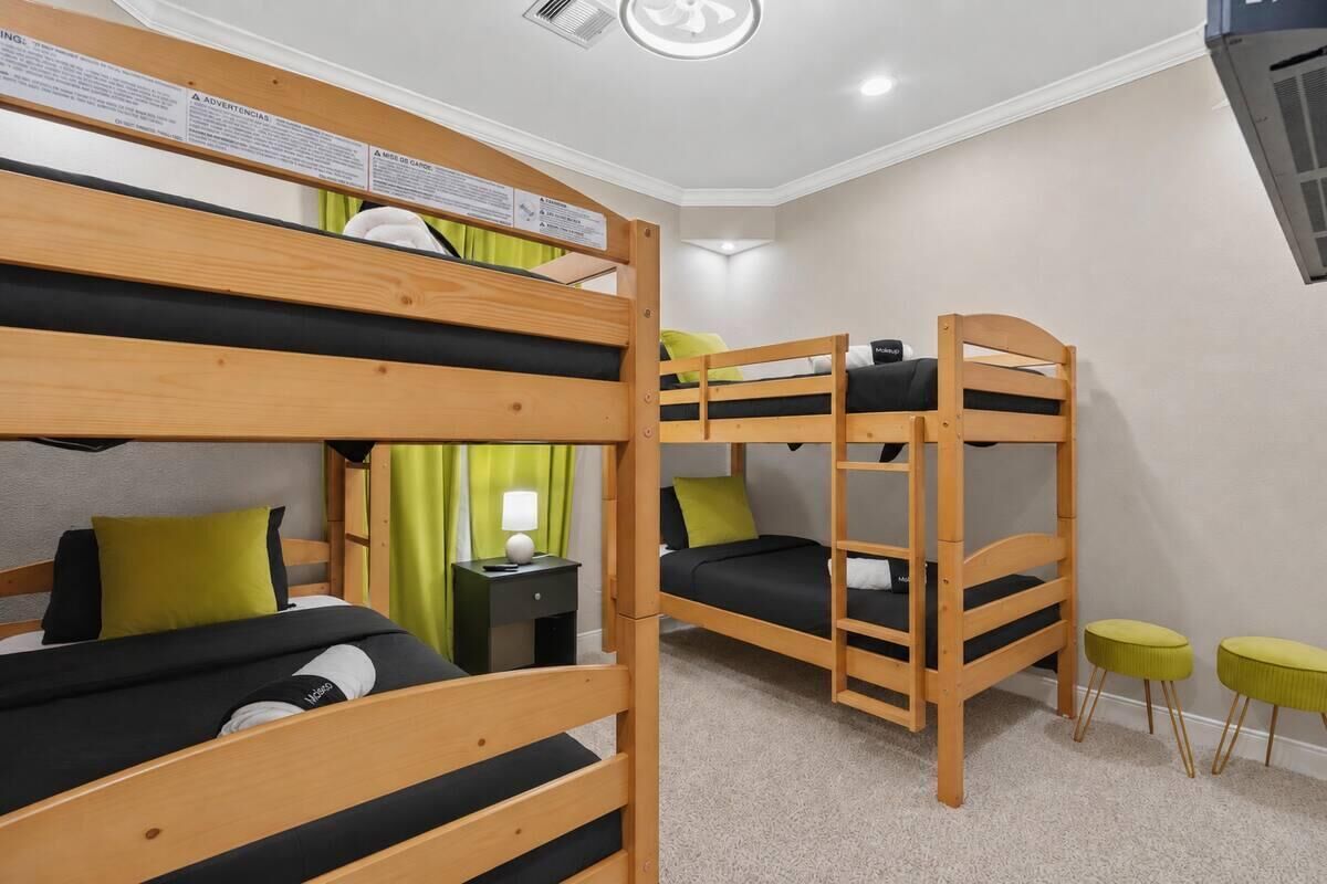A bunk bed room with a nightstand and two stools.