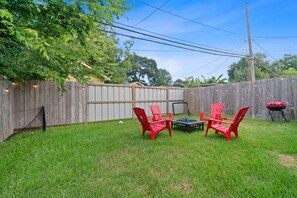 A backyard with a wooden fence, a grill, and red chairs around a table. - Sleeps 14, GameRoom + Sports + Grill, Near Reliant Stadium (Houston)