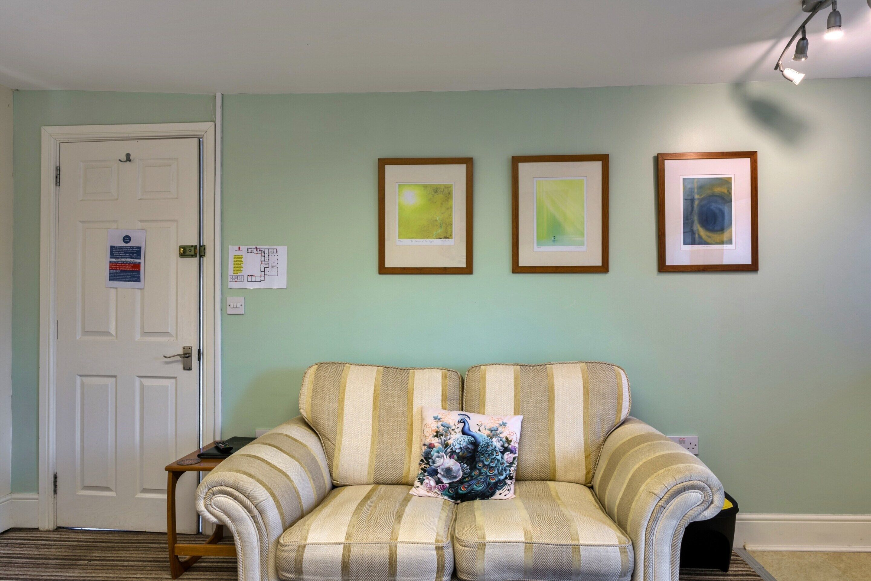 Una habitación con un sofá, una puerta y tres cuadros en la pared.