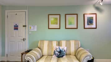 Una habitación con un sofá, una puerta y tres cuadros en la pared.