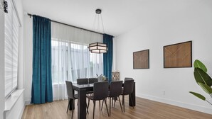 Uma sala de jantar com mesa, cadeiras e luminária pendente.