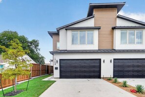 A modern two-story house with a garage, a well-maintained lawn, and a wooden fence. - Luxe 3BR/3.5BA Garage. Patio. Near UTSW & DT (Dallas)