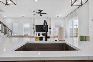 A modern kitchen with a central island, a built-in sink, and a ceiling fan. - Luxe 3BR/3.5BA Garage. Patio. Near UTSW & DT (Dallas)