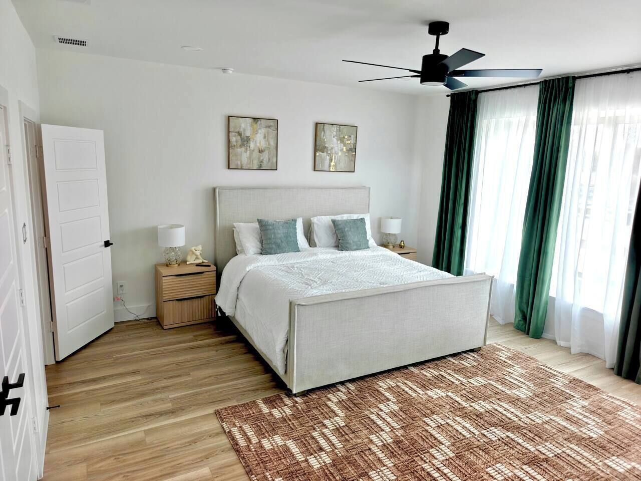 A bedroom with a bed, bedside tables, a ceiling fan, and a window with curtains.