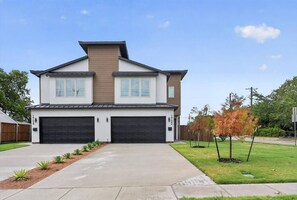A two-story residential house with a garage, a driveway, and a well-maintained lawn. - Luxe 3BR/3.5BA Garage. Patio. Near UTSW & DT (Dallas)