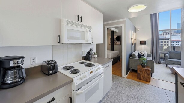 A modern kitchen with a microwave, stove, and coffee maker. - Explore Gaslamp from Chic Loft +Balcony City Views (San Diego)