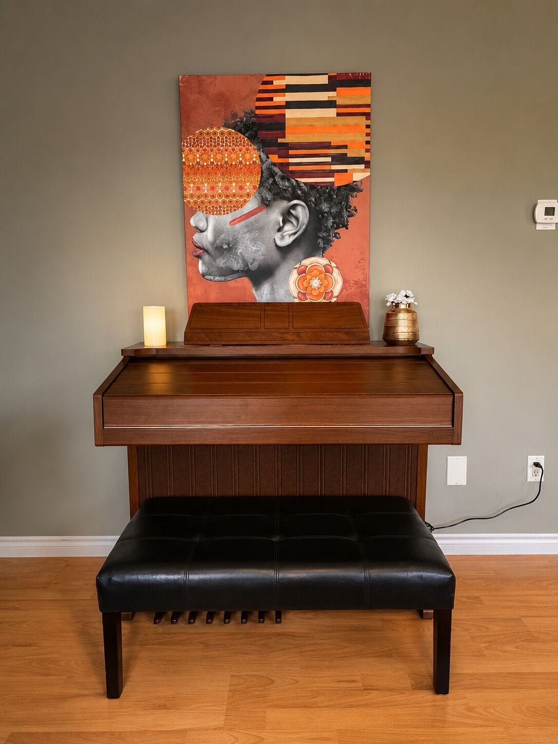 A piano with a bench in front, a wall-mounted light, and a decorative vase on a table.
