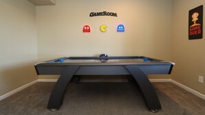 Una mesa de billar con un cartel que dice 'GAME ROOM' encima y un cartel que dice 'GAME OVER' a la derecha.
