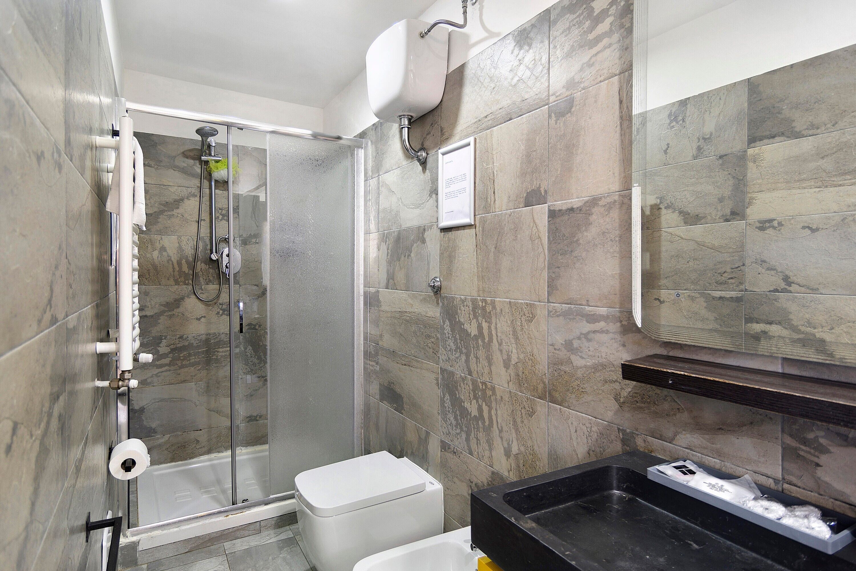 A bathroom with a glass-enclosed shower, a white toilet, and a black sink.