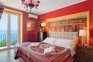 A hotel room with a large bed, a view of the sea, a chandelier, and a painting on the wall. - Villa 'Fuenti Bay' with Sea View, Wi-Fi and Air Conditioning (Vietri sul Mare)