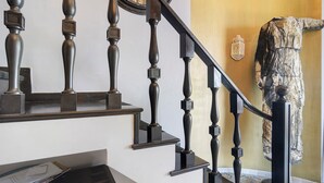 A staircase with dark wooden balusters and a handrail, leading to a landing with a white wall and a mirror.