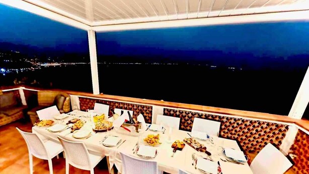 A dining area with a table set for six, chairs, and a view of the city at night.