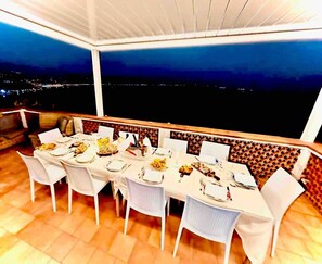 A dining area with a table set for six, chairs, and a view of the city at night.