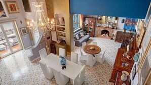 A spacious living area with a chandelier, a fireplace, and a variety of decorative items.