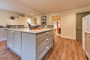 A kitchen with a central island, wooden flooring, and a view into the dining area. - Spacious Cottage Near Denbigh (Denbigh)