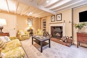 A living room with a fireplace, two armchairs, a coffee table, and a bookshelf. - Spacious Cottage Near Denbigh (Denbigh)