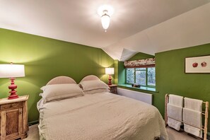 A bedroom with a bed, two bedside tables with lamps, a radiator, a window with a view, and a towel rack. - Spacious Cottage Near Denbigh (Denbigh)