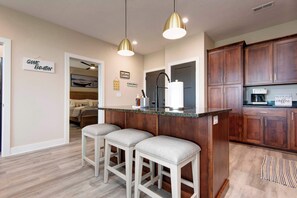 Una cocina moderna con armarios de madera, una isla central con taburetes e iluminación colgante.