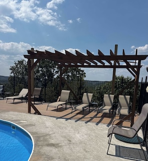 A poolside area with a pergola, lounge chairs, and a swimming pool. - Pam's Place NEW Heated Indoor Pool Splashpad  SDC (Branson)