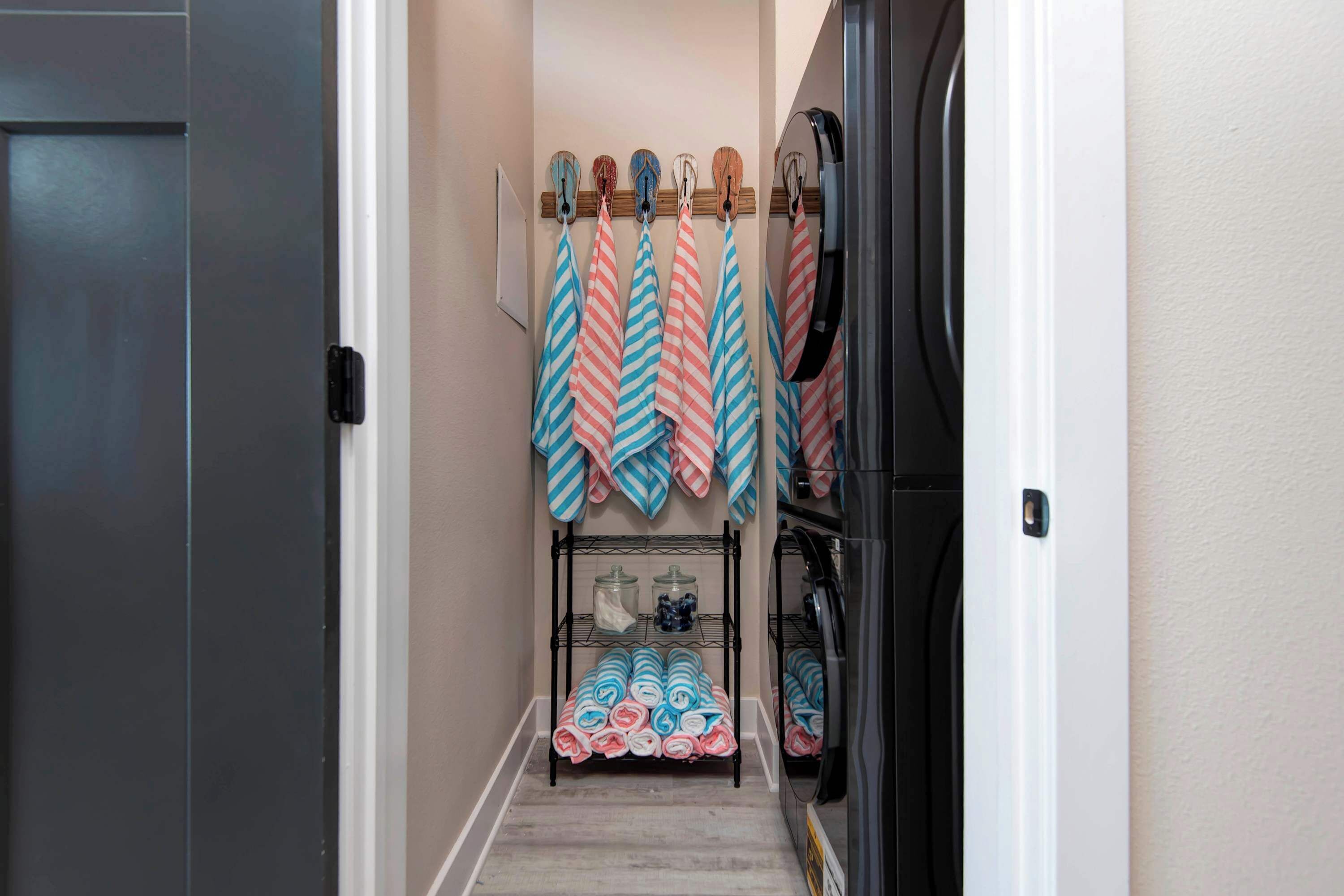 Un couloir étroit, avec un présentoir métallique où sont pliées des serviettes et une petite étagère sur laquelle sont posés des pots.