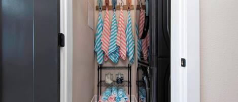 Un couloir étroit, avec un présentoir métallique où sont pliées des serviettes et une petite étagère sur laquelle sont posés des pots.
