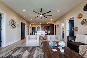 A spacious living room with a ceiling fan, a dining area with a table and chairs, and a kitchen in the background. - BWV 241 Pam's Place (Branson)