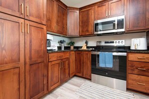 A kitchen with wooden cabinets, a microwave, an oven, and a coffee maker. - BWV 241 Pam's Place (Branson)