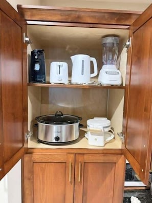 A kitchen with wooden cabinets, a coffee maker, a toaster, a blender, a slow cooker, and a kettle. - Pam's Place NEW Heated Indoor Pool Splashpad  SDC (Branson)
