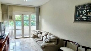 Un salón con sofá, sillas, televisor y una obra de arte en la pared.