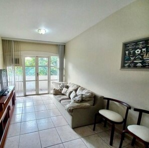 A living room with a sofa, chairs, a TV, and a wall art piece. - Apartment in Guaruja Enseada (300m from the sea) (Guarujá)