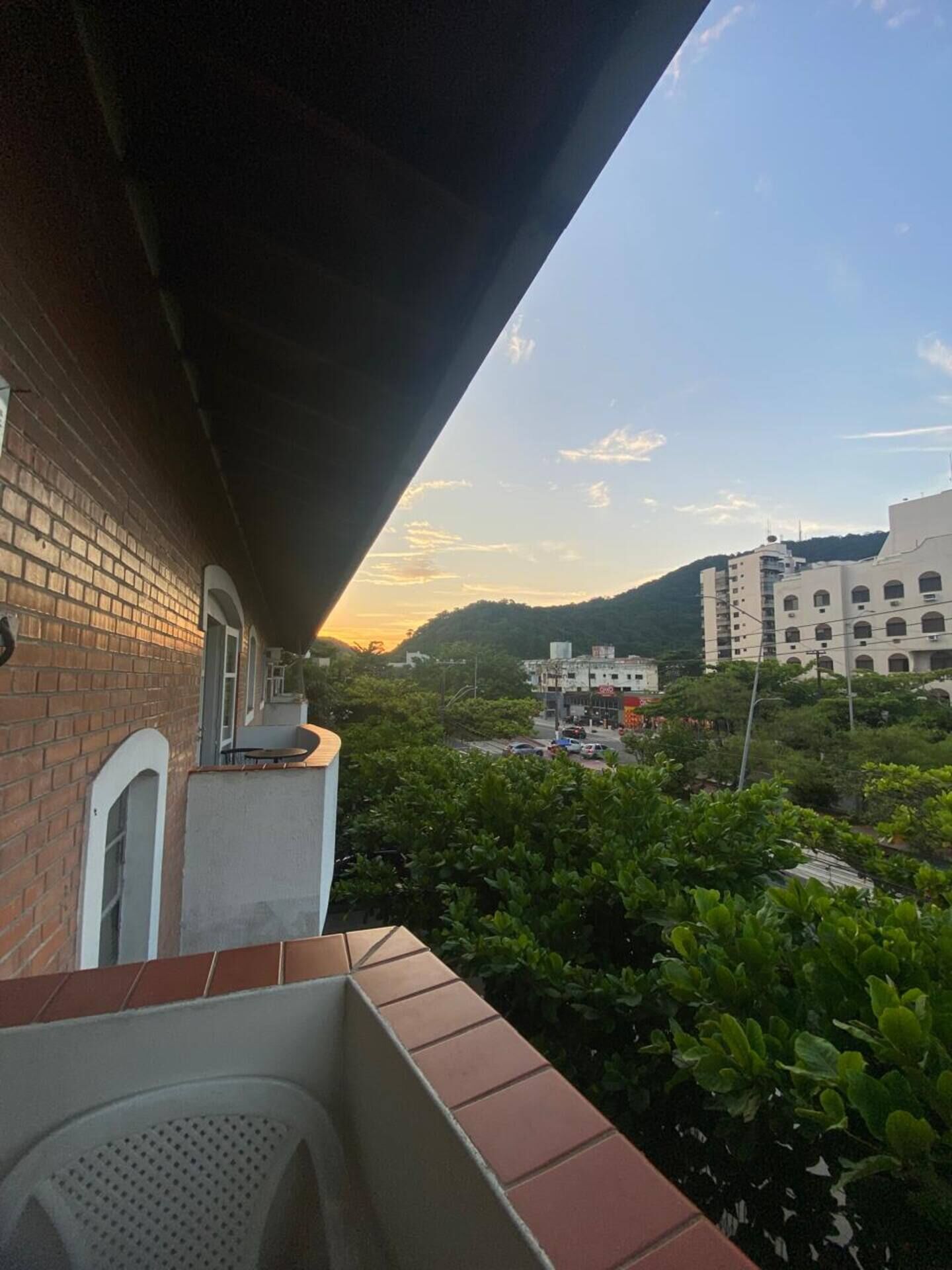 Un balcon offrant une vue sur le paysage urbain et les montagnes au coucher du soleil.