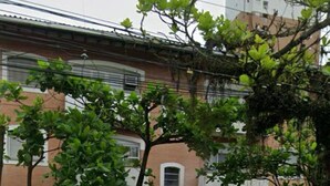 Un edificio residencial con fachada de ladrillo, marcos de ventana blancos y una valla de metal blanca.