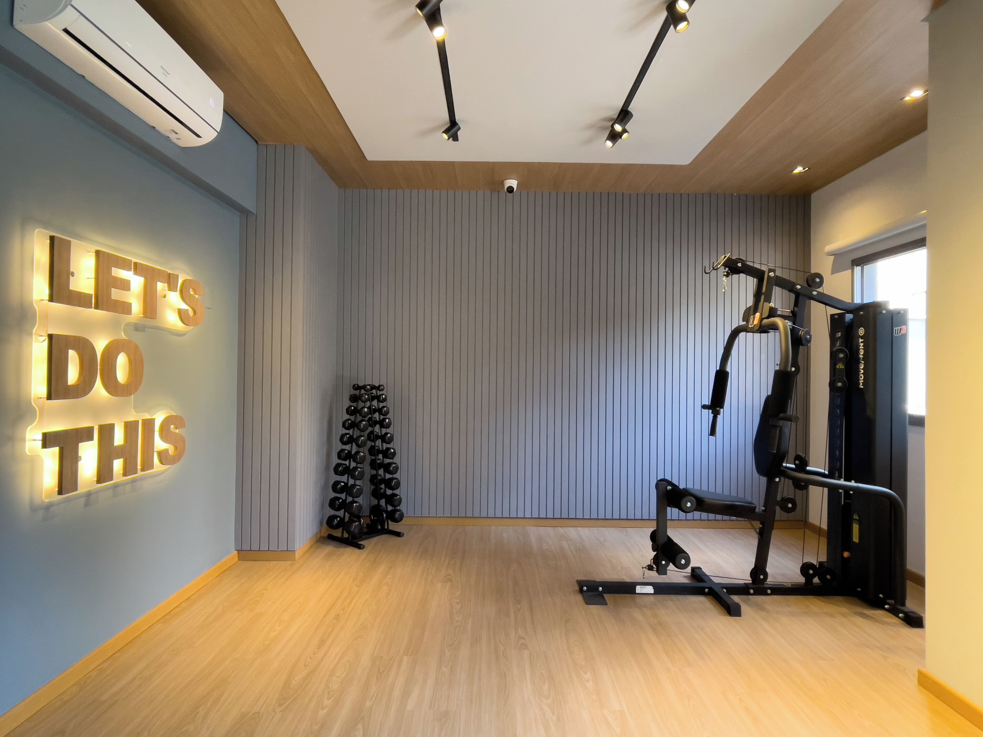 A gym with a motivational wall, exercise equipment, and a wooden floor.