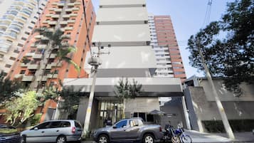 Edifício de vários andares com design moderno, destacando uma entrada imponente com porta de vidro e uma pequena cobertura.