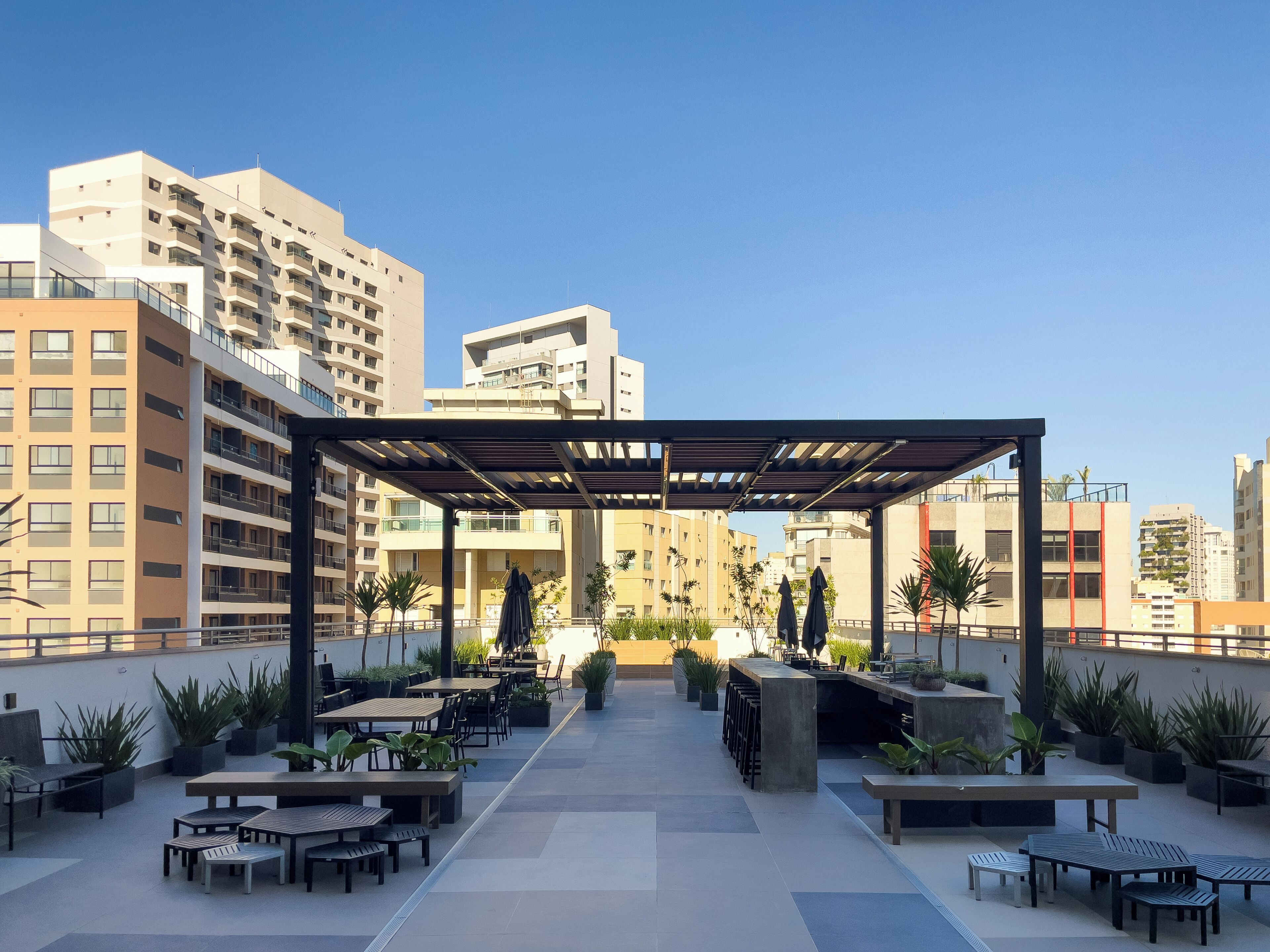 Terraza en la azotea con mobiliario exterior, rodeada de edificios altos.