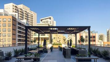 A rooftop patio with outdoor seating, surrounded by high-rise buildings.