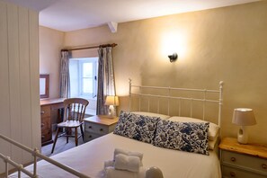 Ein Schlafzimmer mit einem Bett, einem Schreibtisch, einem Stuhl und einem Fenster mit Vorhängen.