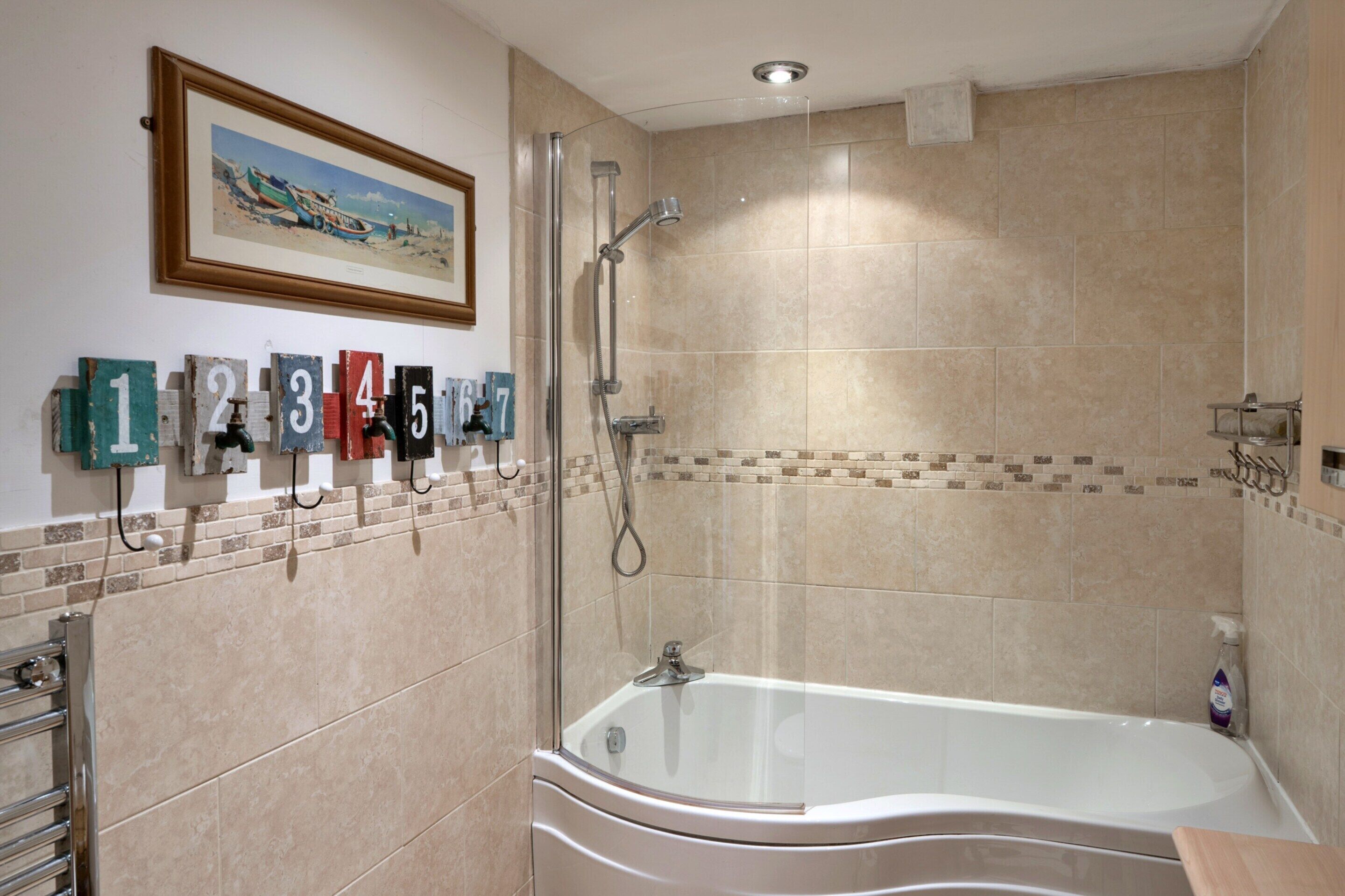 Un baño con bañera, ducha y pared revestida de azulejos con letreros numerados.