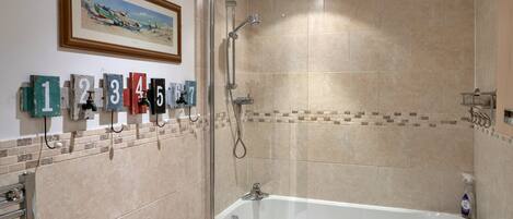 Un baño con bañera, ducha y pared revestida de azulejos con letreros numerados.