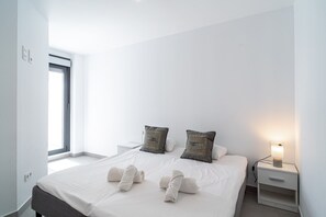 Ein Hotelzimmer mit einem großen Bett, zwei Kissen, einem Nachttisch mit Lampe und einem Fenster mit Jalousien.