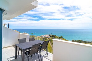 Ein Balkon mit Tisch und Stühlen mit Blick auf die Küste.